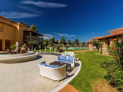 Moderní venkovní prostor hotelu s posezením, fontánou a udržovaným trávníkem za jasné oblohy