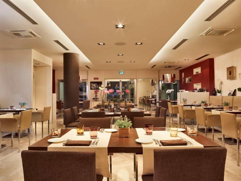 Area ristorante dell'hotel dal design moderno con tavoli apparecchiati e sedie confortevoli.