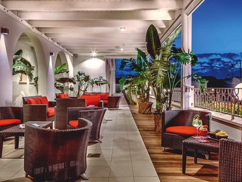 Accogliente terrazza dell'hotel con posti a sedere, piante e vista sul cielo serale.