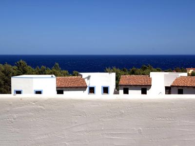 Bâtiments blancs avec toits en tuiles rouges devant la mer bleue et le ciel clair