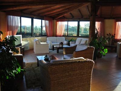 Cozy lounge area with wicker furniture and large windows overlooking greenery in a hotel.