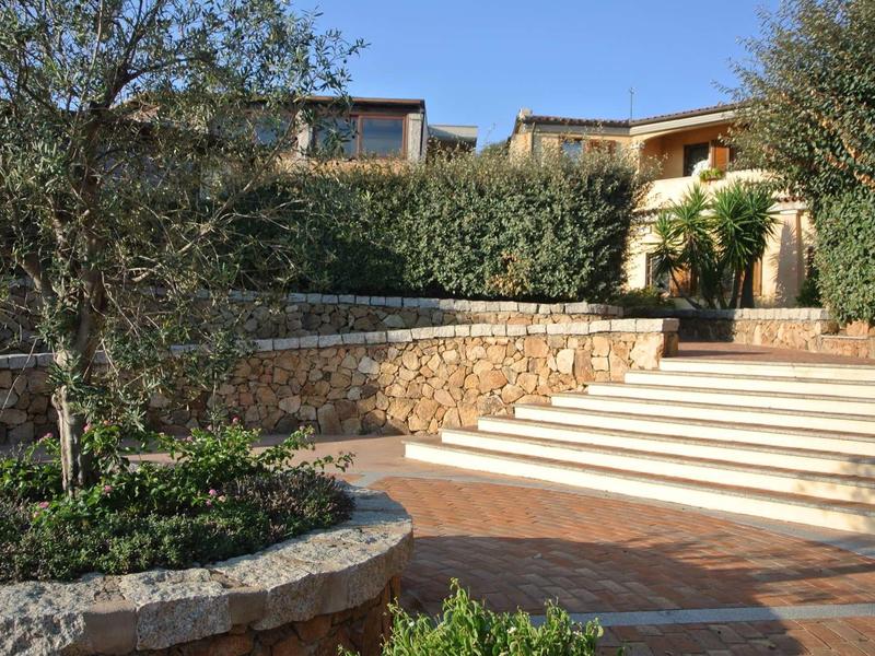 Outdoor area of a hotel with plants, stone walls, and light steps leading to the terrace.