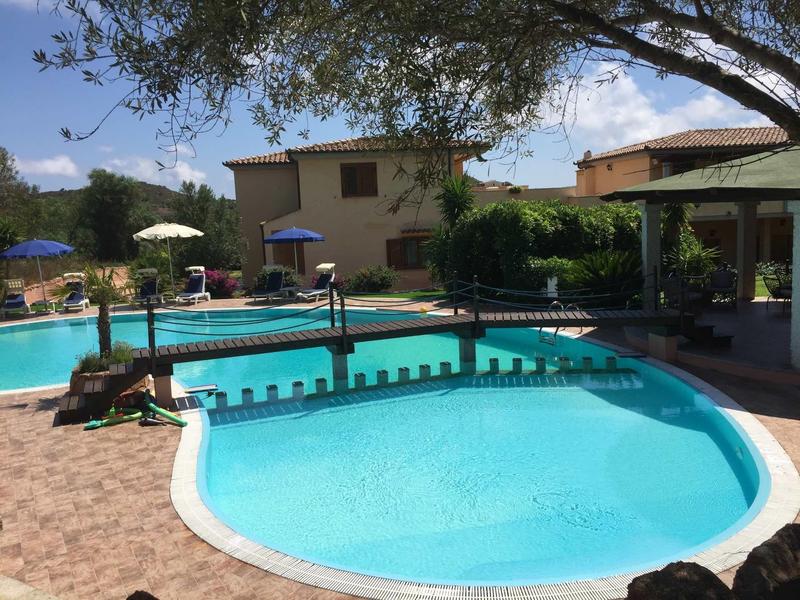 Leisure pool with bridge in quiet hotel garden on sunny day.