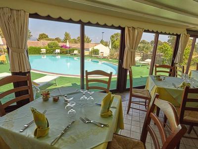 Restaurant avec vue sur la piscine, table dressée avec couverts et serviettes.
