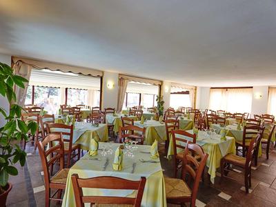 Grande salle à manger avec de nombreuses tables et chaises, dressées avec des nappes jaunes.
