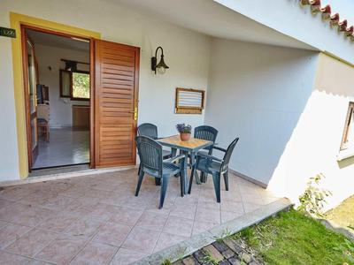 Terrasse avec table de jardin et chaises devant une maison avec porte ouverte