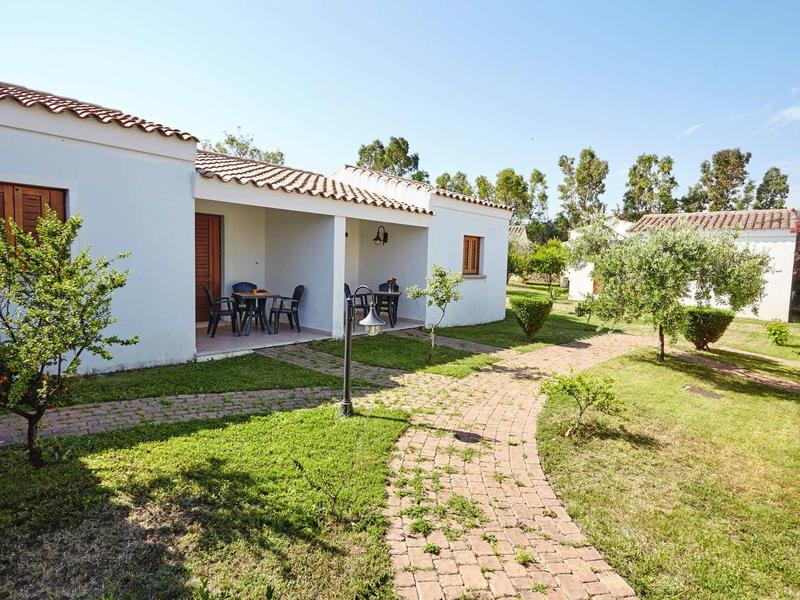 Maison en rangée blanche avec petit jardin et sentier pavé sous un ciel clair