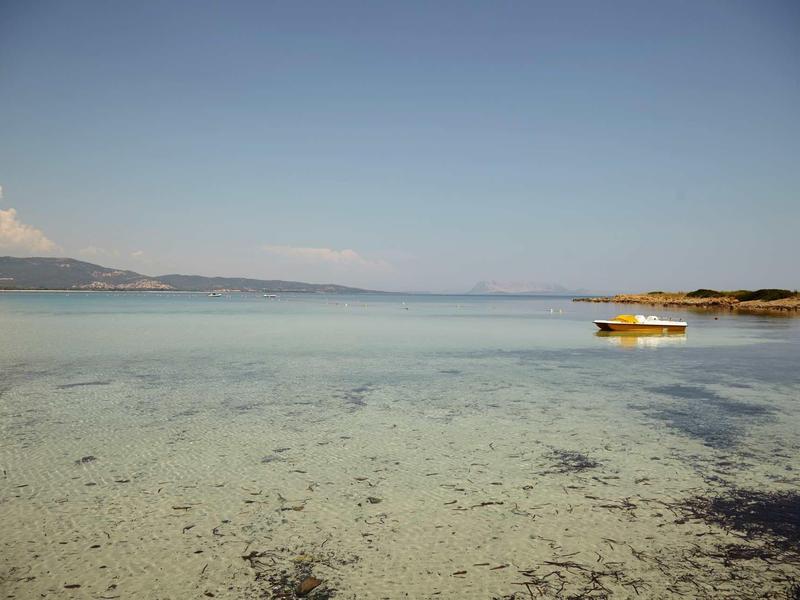 Eau peu profonde claire avec un bateau jaune et un vaste ciel près de la côte.