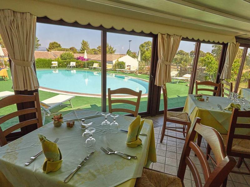 Table de restaurant dressée avec couverts donnant sur une piscine et un jardin