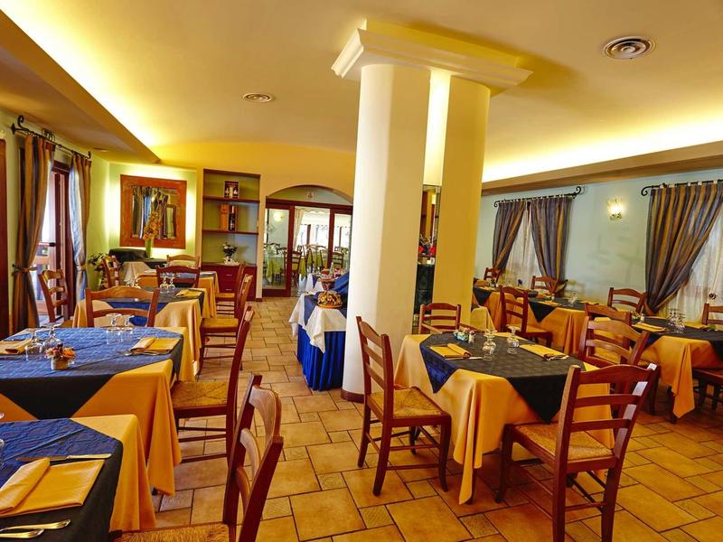 Salle à manger accueillante avec murs jaunes, nappes bleues et chaises en bois dans un hôtel.