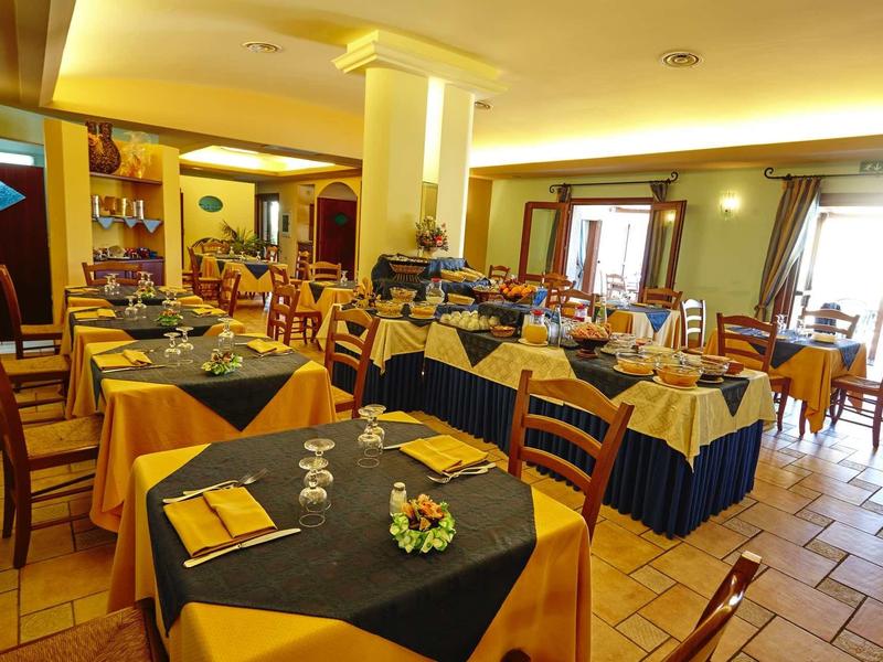 Restaurant d'hôtel lumineux avec murs jaunes, chaises en bois et tables décorées.