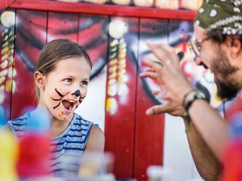 Fille avec peinture de visage de chat jouant avec un homme faisant des gestes de griffes.