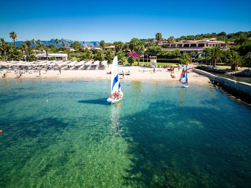 Voiliers près d'une plage de sable avec des chaises longues sous un ciel bleu