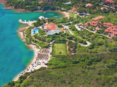 Luchtfoto van een kustresort met strand, zwembad en groene gebieden.