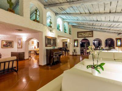 Gezellige lounge met witte banken, piano en grote bogen ramen.