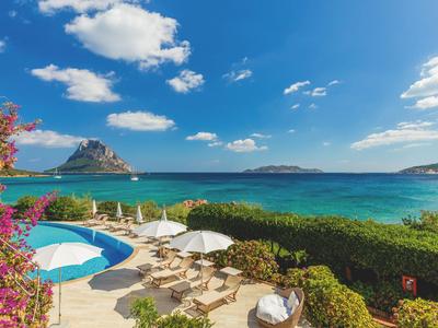 Vue d'une terrasse d'hôtel avec piscine et transats au bord de la mer par une journée ensoleillée