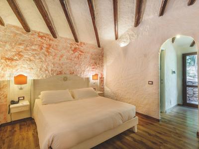 Gezellig tweepersoonsbed in rustieke kamer met zichtbare bakstenen muren en houten balken.