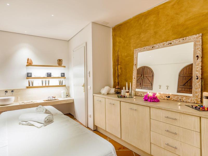 Gezellige behandelruimte met massagetafel, warme kleuren en grote spiegel.