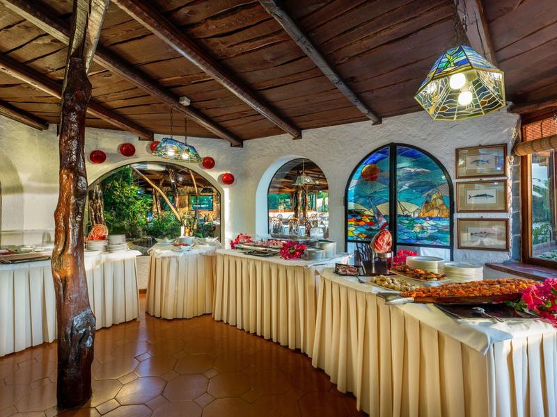 Gezellig buffetgedeelte met versierde tafels en grote ramen met uitzicht op groene natuur.