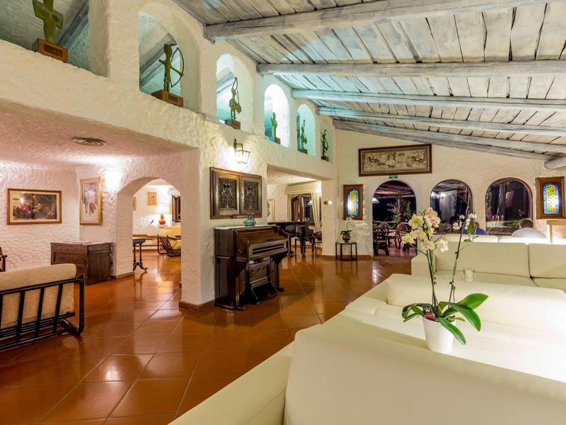 Gezellige lounge met witte banken, piano en grote bogen ramen.