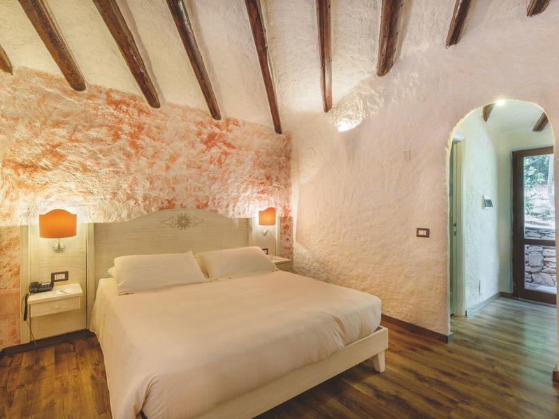 Gezellig tweepersoonsbed in rustieke kamer met zichtbare bakstenen muren en houten balken.