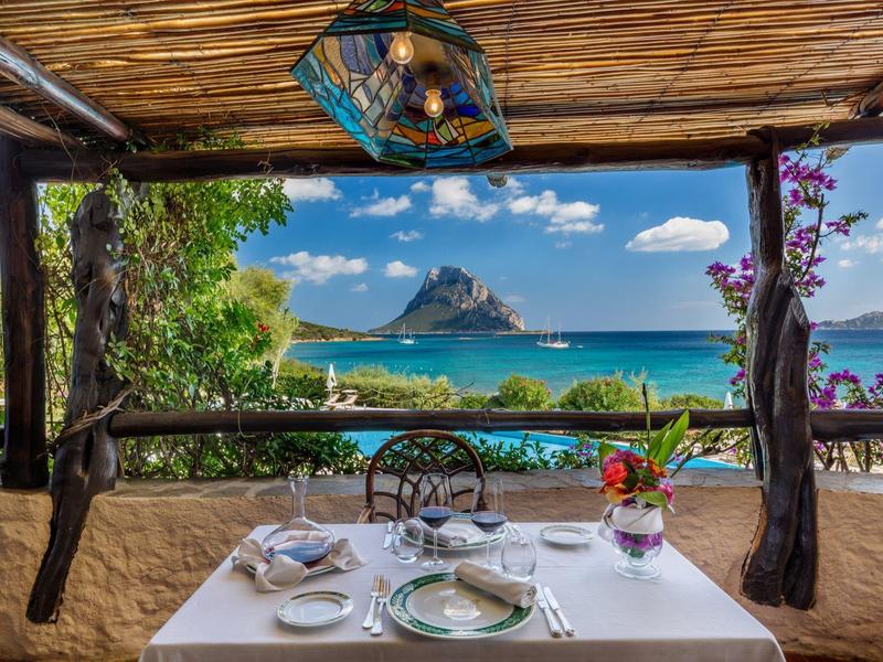 Romantisch gedekte eettafel met uitzicht op zee en een rotsachtig eilandberg.