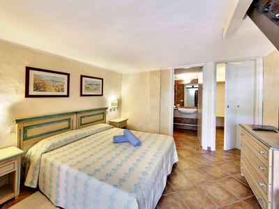 Chambre d'hôtel lumineuse avec lit double, deux tableaux, lampes de chevet et télévision.