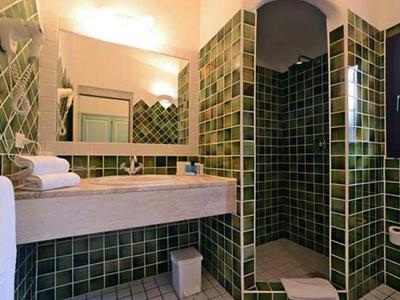 Koupelna se zelenými obklady, dřevěnou deskou, zrcadlem, ručníky a sprchovým koutem.