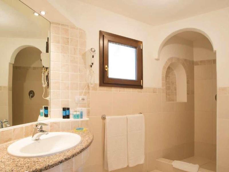 Koupelna se umyvadlem, zrcadlem, oknem, držákem na ručníky a sprchou s obložením.