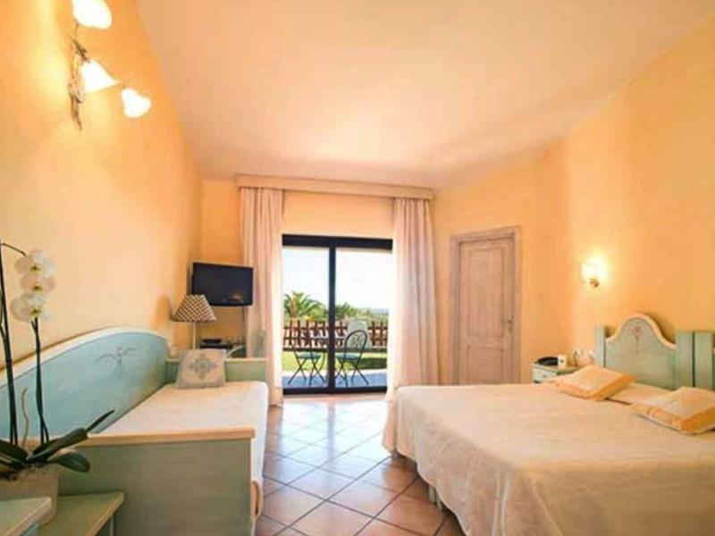 Pohodlný hotelový pokoj s manželskou postelí, balkonem, televizí a pastelovým nábytkem.