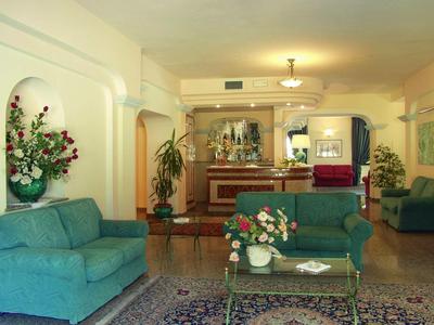 Accogliente area lounge dell'hotel con divani, tavolo e composizioni floreali.