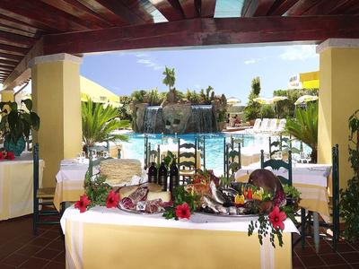 Area esterna coperta con tavolo decorato e vista sulla piscina dell'hotel con cascata.