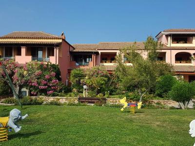 Zelený trávník s hračkami před středomořskou budovou s balkóny