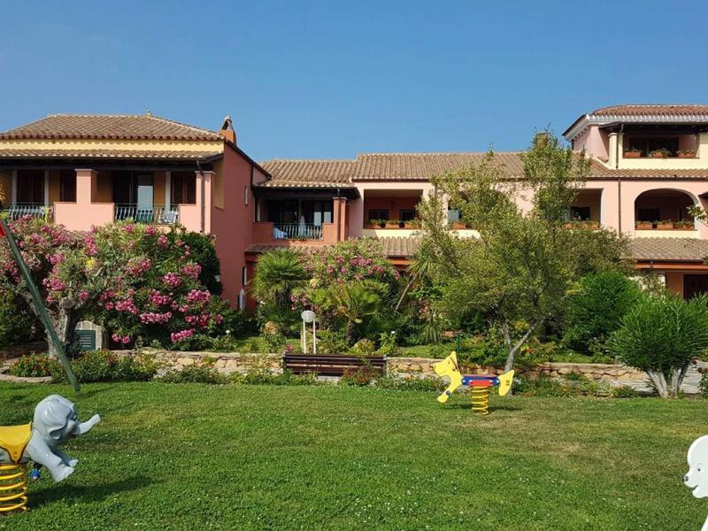 Zelený trávník s hračkami před středomořskou budovou s balkóny