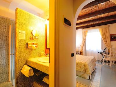 Gezellige hotelkamer met tweepersoonsbed, bureau en gouden verlichting in de badkamer.