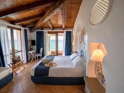 Gezellige hotelkamer met houten balkenplafond, tweepersoonsbed en balkon met zeezicht.