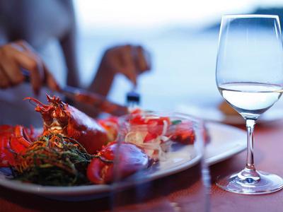 Copa de vino junto a un plato de mariscos y cangrejos sobre una mesa.