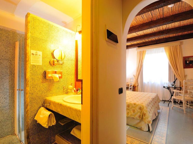 Gezellige hotelkamer met tweepersoonsbed, bureau en gouden verlichting in de badkamer.