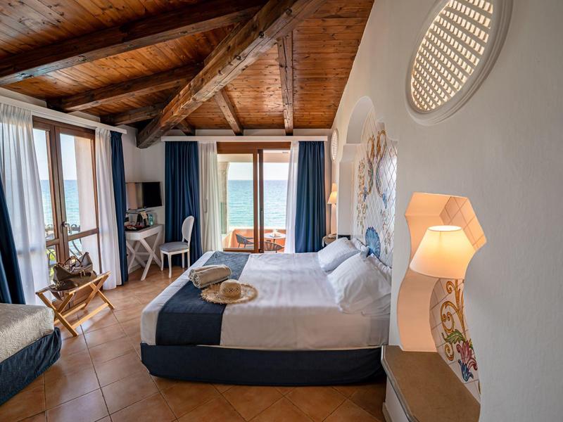 Gezellige hotelkamer met houten balkenplafond, tweepersoonsbed en balkon met zeezicht.