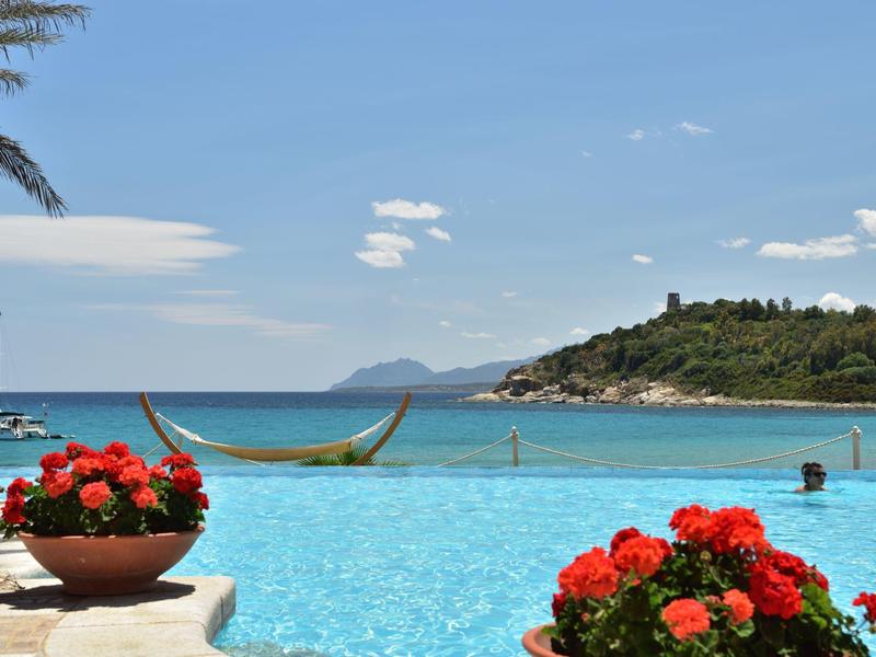 Infinity zwembad met uitzicht op zee en bloeiende rode bloemen op de voorgrond.