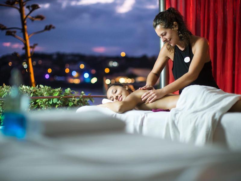 Ontspannende buitenmassage bij schemering met uitzicht op de stad.