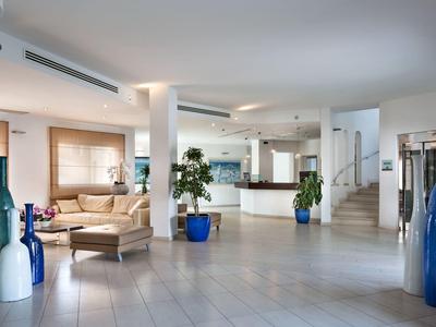 Helle Hotellobby mit moderner Einrichtung, Loungebereich und weißen Fliesen.