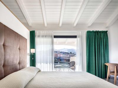 Modernes Hotelzimmer mit großem Fenster, grünem Vorhang und Bergblick