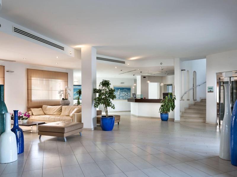 Helle Hotellobby mit moderner Einrichtung, Loungebereich und weißen Fliesen.