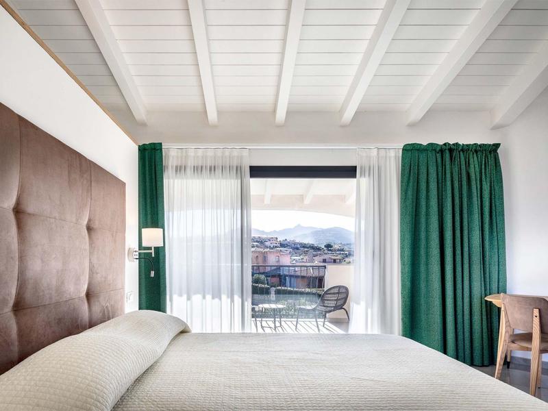 Modernes Hotelzimmer mit großem Fenster, grünem Vorhang und Bergblick