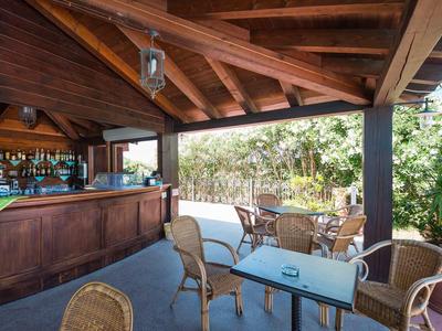 Gezellige bar met houten dak en zitgedeelte omgeven door groen in een hotelomgeving.