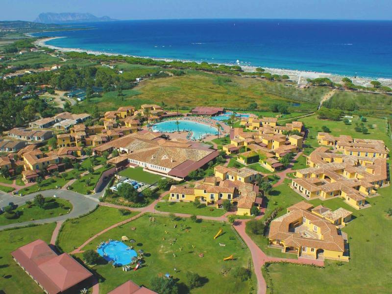 Luchtfoto van een vakantieoord met meerdere gebouwen, zwembaden en dicht bij de zee.