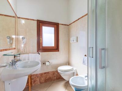 Small bathroom with shower, sink, toilet, and bidet in light colors.