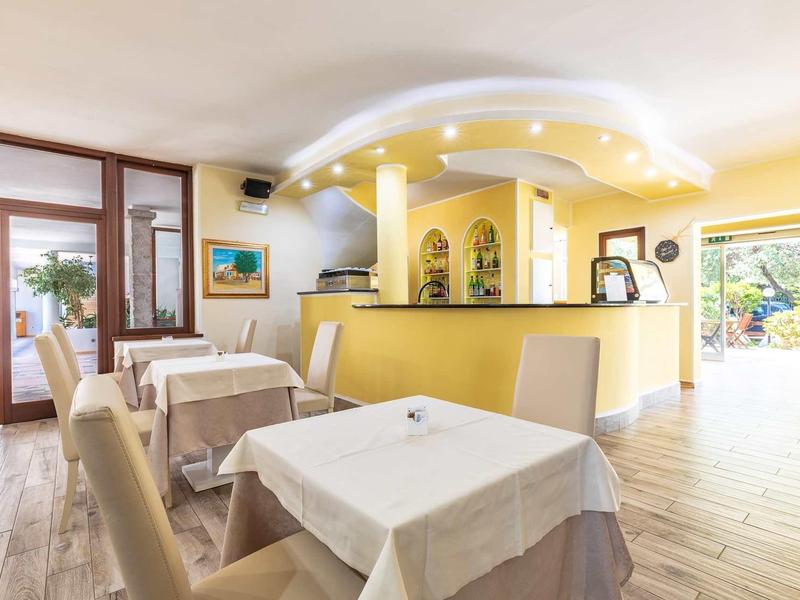 Bright restaurant with set tables and a reception counter near a terrace.