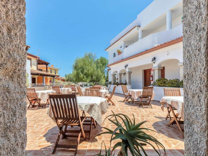 Hotel terrace with tables, chairs, and white tablecloths in sunny weather.